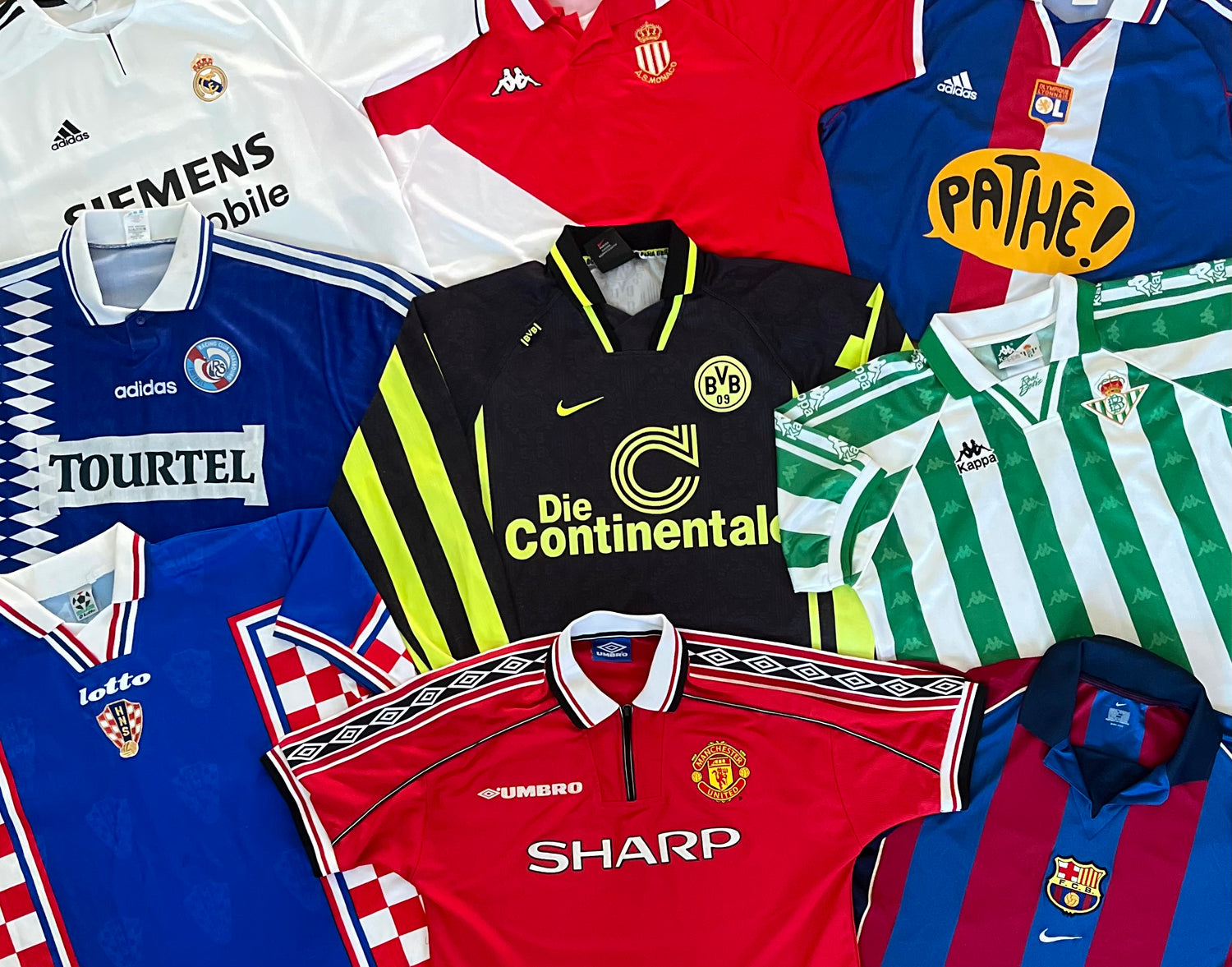 Multiple football shirts laid out, showcasing cool designs from popular teams such as Barcelona, Manchester United, and Real Madrid.